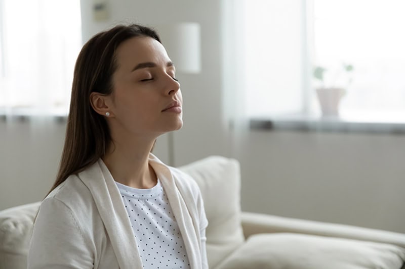 woman meditating in her home on her couch.