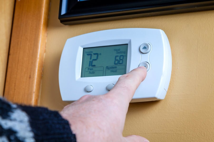 Homeowner lowering their thermostat fan settings for more comfortable indoor air.