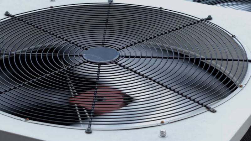 View of air conditioner fan spinning on air conditioning unit.