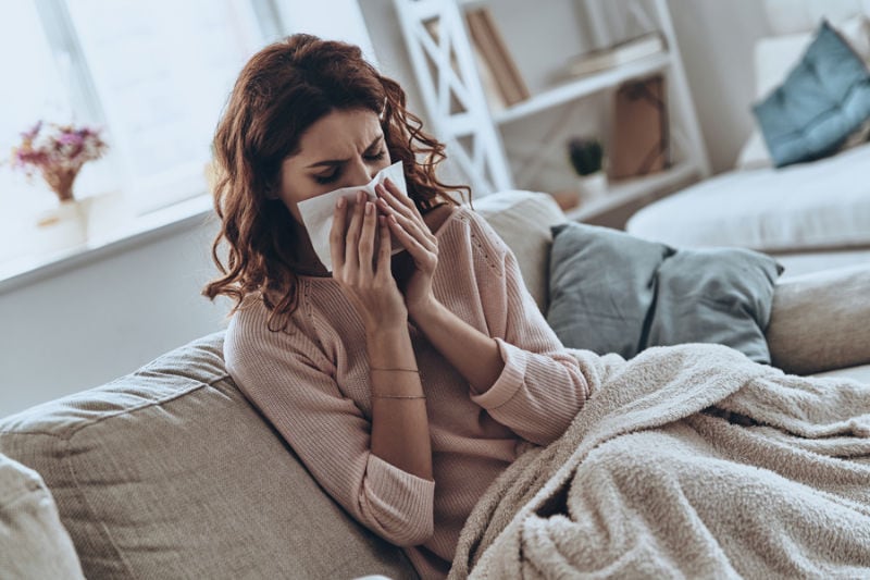 Woman blowing nose due to dust in home.