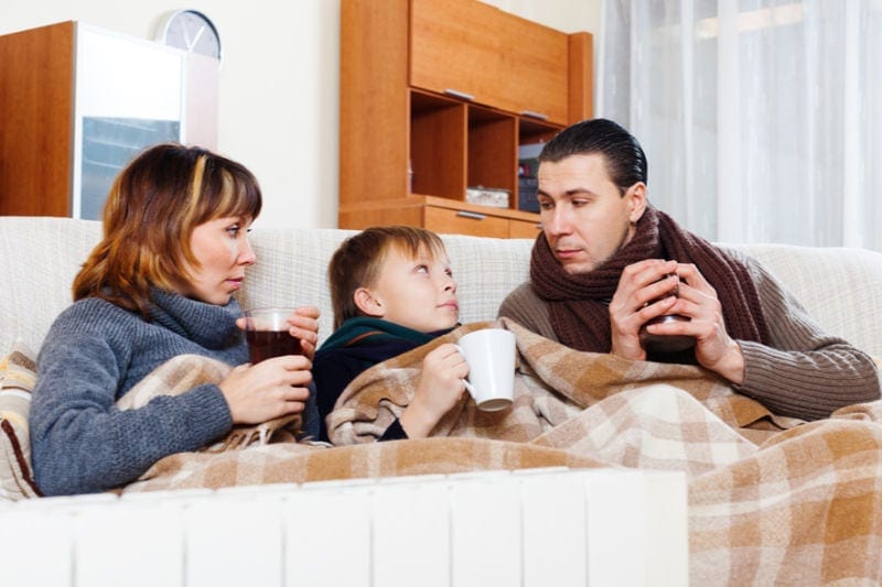 Cold family under blanket with coffee and hot chocolate, trying to stay warm.