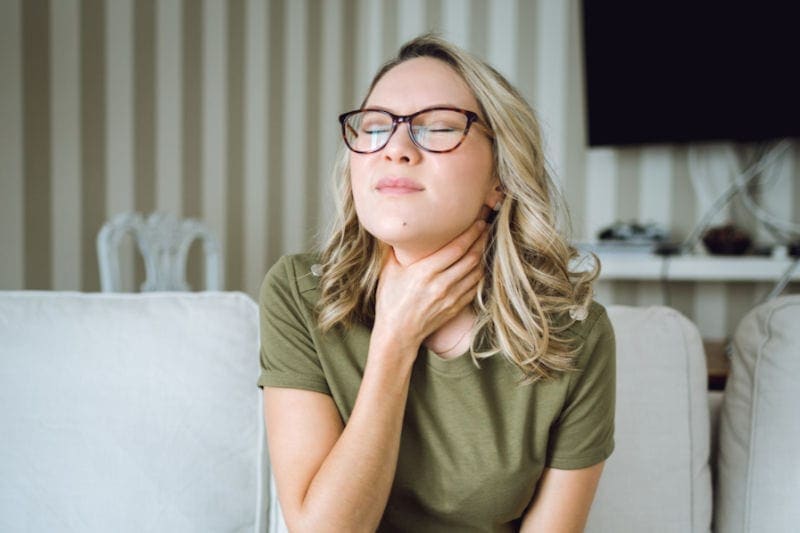 Woman with sore throat due to her home's poor indoor air quality. Air-Ton Heating & AC blog image.